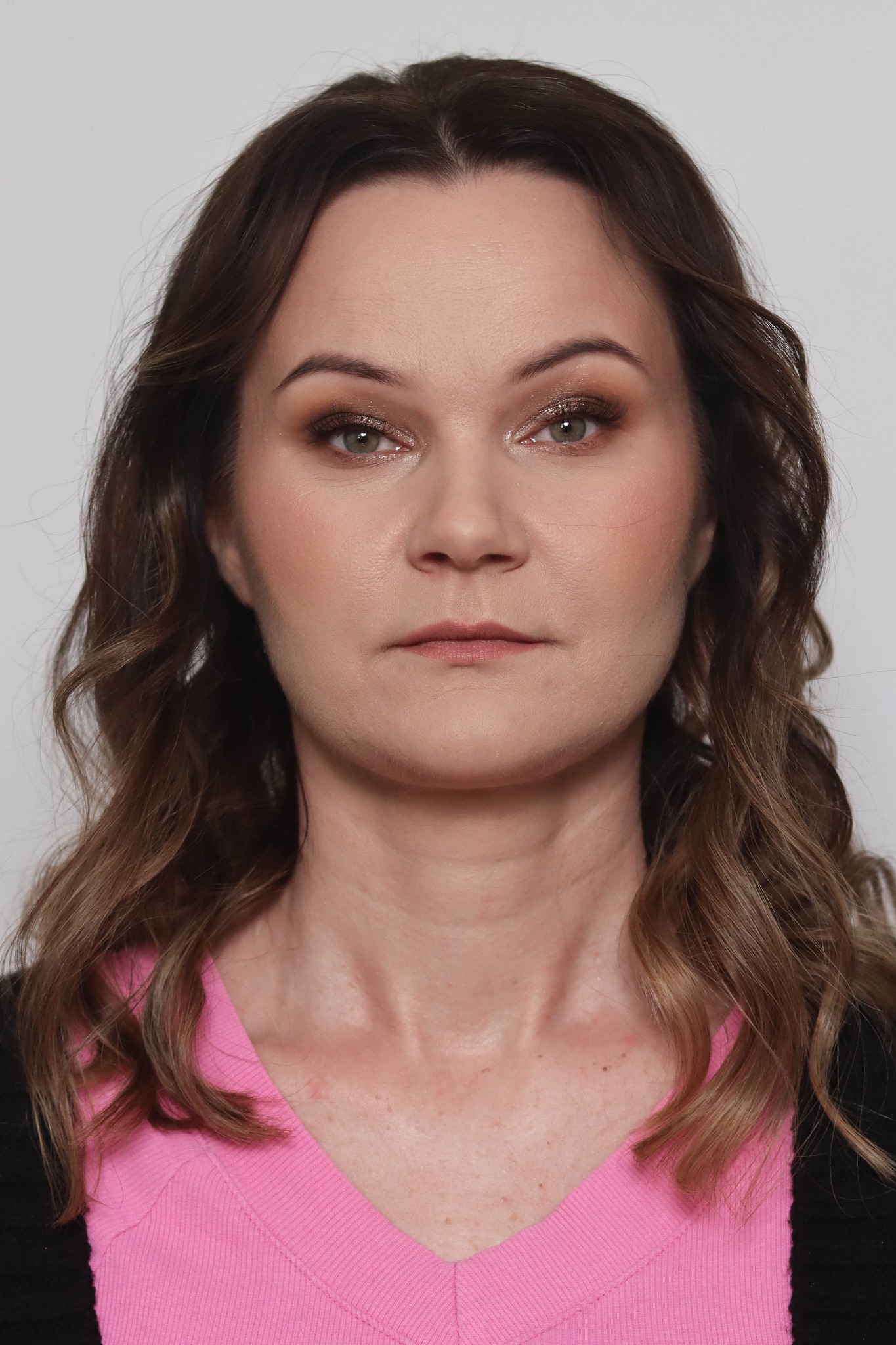 Portret kobiety z delikatnym makijażem dziennym, uwydatnione brązowe cienie na powiekach i subtelny róż na policzkach, włosy brązowe z refleksami.