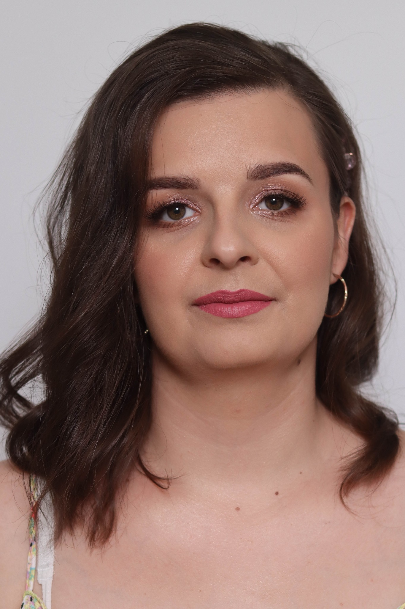 Portret kobiety z delikatnym, różowym cieniem na powiekach, matową pomadką w odcieniu dusty rose i subtelną spinką we włosach.