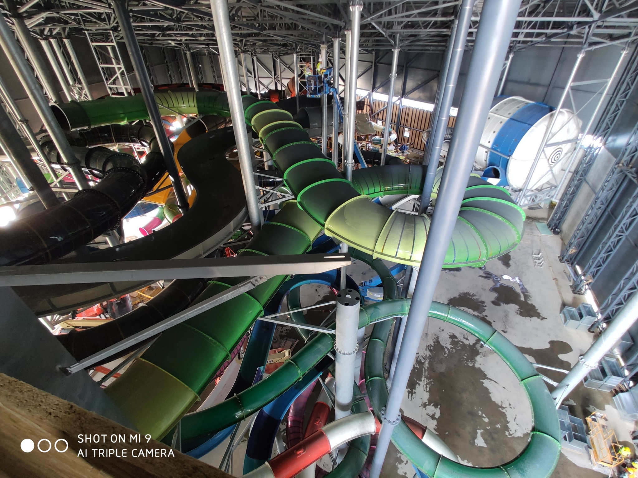 Wysoka konstrukcja z wieloma kolorowymi zjeżdżalniami wodnymi w parku wodnym, widok z góry, elementy stalowe konstrukcji nośnej.