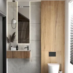 Nowoczesna łazienka z drewnianą szafką pod umywalką i dużym lustrem z podświetleniem LED, minimalistyczna toaleta w zabudowie, szare płytki na ścianach i podłodze, dekoracyjne trawy w wazonie.