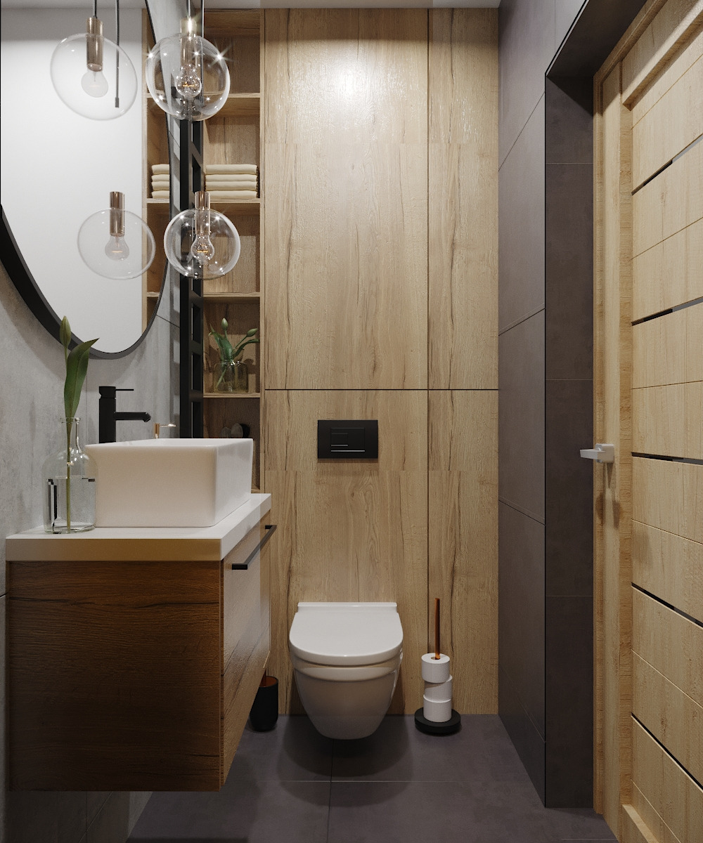 Nowoczesna łazienka z drewnianymi akcentami: wisząca szafka pod umywalką z blatem, okrągłe lustro z dekoracyjnymi lampami, toaleta podtynkowa i drewniane panele ścienne.