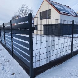 Inter-Style - Nowoczesne ogrodzenie panelowe w kolorze antracytowym, łączące przęsła z poziomymi lamelami i siatką, otaczające nowe domy na zaśnieżonym terenie.