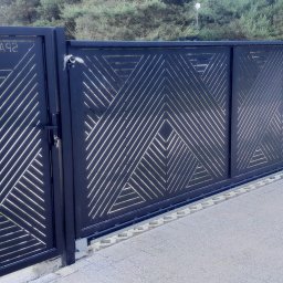 Zybi-pol zakład usługowo produkcyjny - Czarna, przesuwna brama wjazdowa z geometrycznym wzorem szczelin, widoczny zamek i mechanizm przesuwny, na tle ogrodzenia z siatki i zieleni.