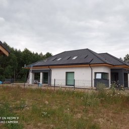 Elektroinstalacje - Dom jednorodzinny z panelami FullBlack na dachu, widoczna drabina oparta o dach oraz fragment budynku w trakcie budowy.