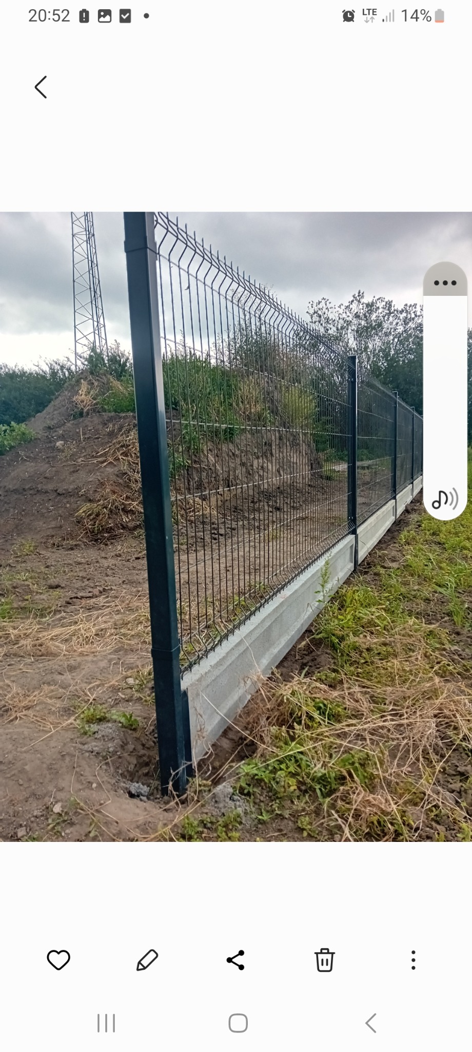 Nowoczesne, ciemne ogrodzenie z siatki panelowej na betonowej podmurówce, świeżo zamontowane w Szamotułach, z widocznym wykopem i ziemią wokół.