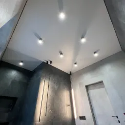 Nowoczesna łazienka z białym sufitem napinanym, punktowym oświetleniem LED i grafitowymi płytkami. Minimalistyczny design z oświetleniem dekoracyjnym.