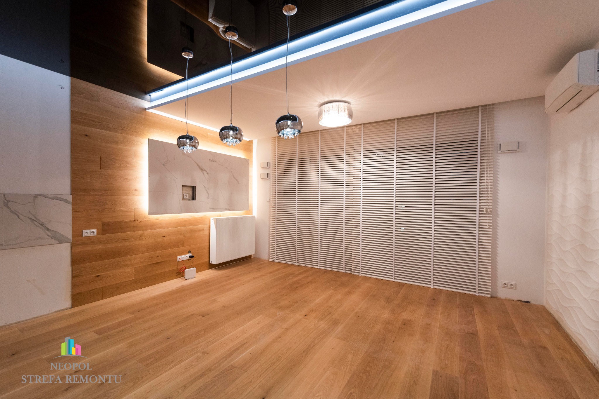 Nowoczesne wnętrze pokoju z drewnianą podłogą, ścianą z paneli drewnianych i marmurowych, oświetleniem LED na suficie i trzema wiszącymi lampami z chromowanymi kloszami, oraz białymi żaluzjami...