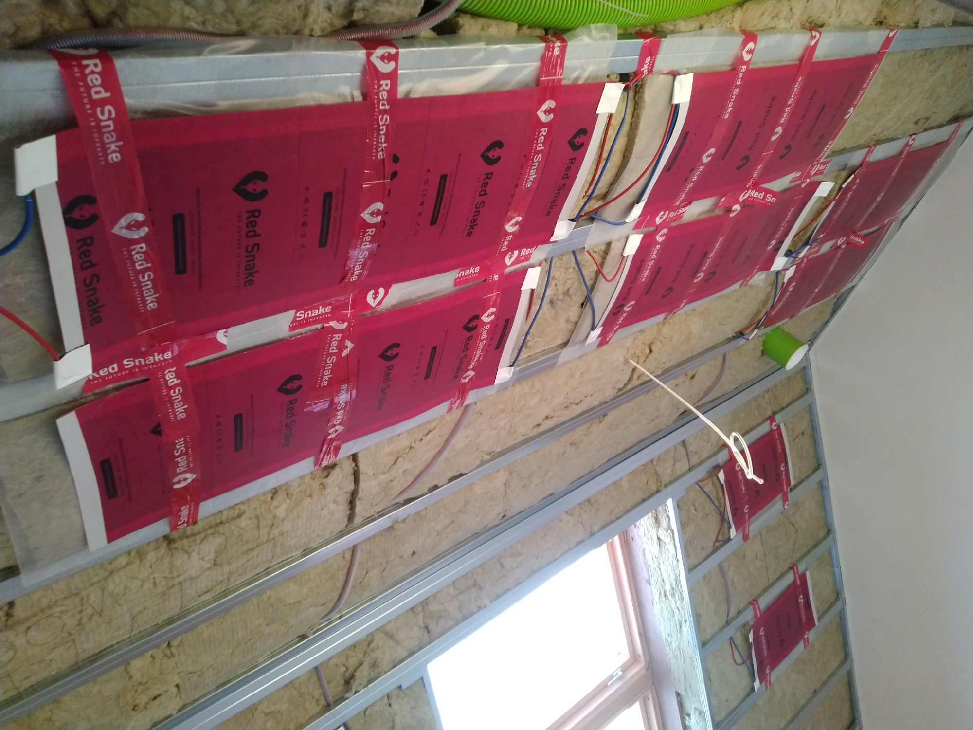 Montaż paneli grzewczych Red Snake na poddaszu, widoczne izolacja, metalowa konstrukcja i okablowanie.