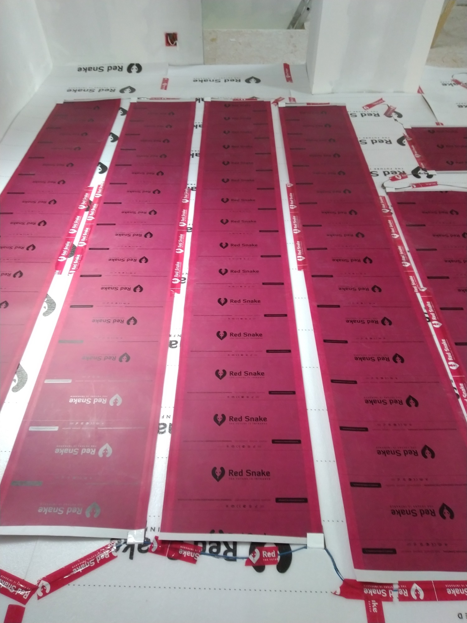 Rozłożona folia podłogowa grzewcza Red Snake z widocznymi elementami grzejnymi i logo producenta, przygotowana do montażu.