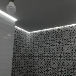 Białe płytki ścienne z dekoracyjnym wzorem, oświetlone listwą LED pod sufitem, widok na narożnik pomieszczenia z żarówką.