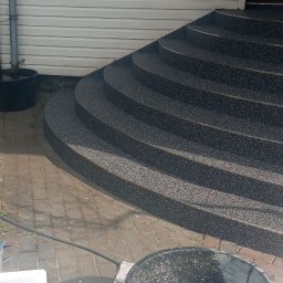 Grzegorz Pepliński - Wykończone schody wejściowe z żywicy epoksydowej w kolorze grafitowym, widoczne narzędzia i wiaderka po pracy. Elewacja budynku z sidingu.