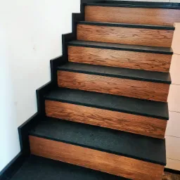 Schody z ciemnego kamienia z drewnopodobnymi nakładkami, widok z dołu, minimalistyczny design.