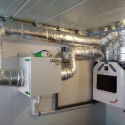 Kompletna instalacja systemu wentylacji mechanicznej z odzyskiem ciepła (rekuperacji) marek WanAs i Zehnder, widoczna w pomieszczeniu w Przędzel, z izolowanymi przewodami wentylacyjnymi...