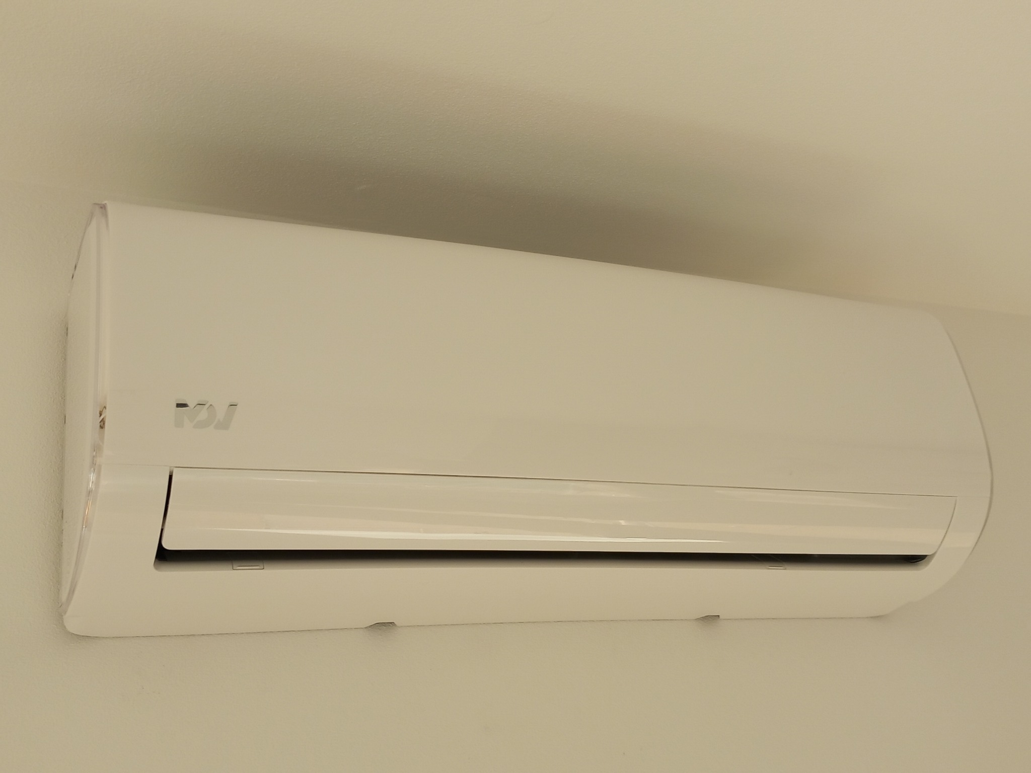 Biała jednostka wewnętrzna klimatyzatora z widocznym logo producenta zamontowana na ścianie o jasnym odcieniu.