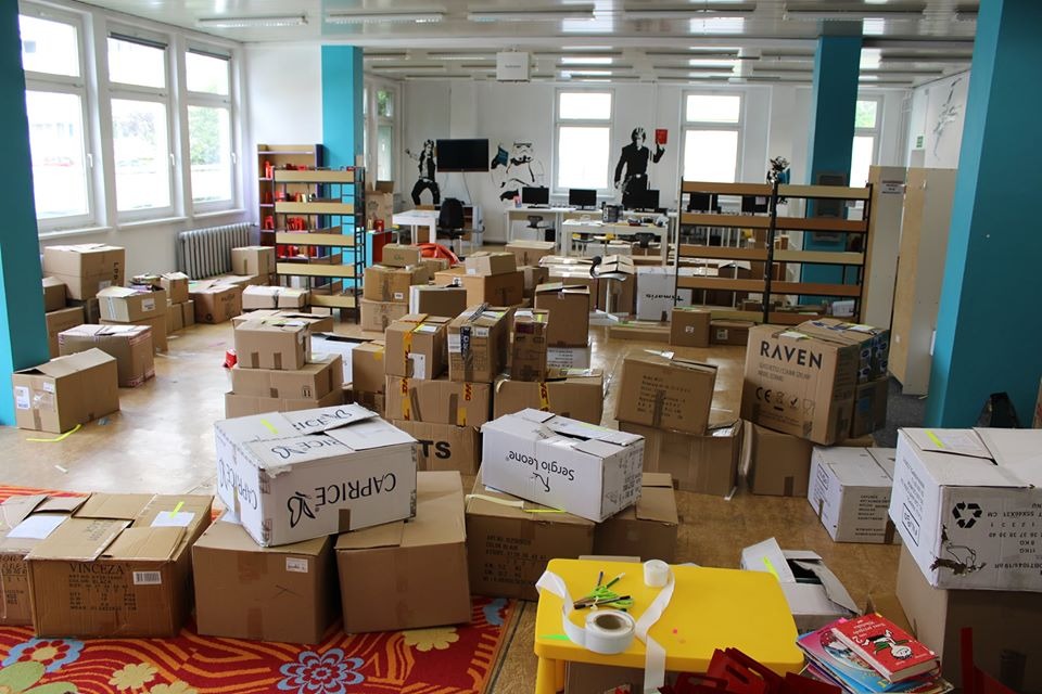 Sala biurowa z kartonami do pakowania, przygotowana do transportu, widoczne biurka i regały z książkami, na ścianach grafiki, na pierwszym planie kartony z napisami 'Caprice', 'Sergio Leone'...
