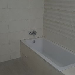 Dream House - Nowoczesna, minimalistyczna łazienka z wanną obudowaną płytkami ceramicznymi, ściany wyłożone jasnymi płytkami o zróżnicowanej fakturze, chromowana bateria wannowa.