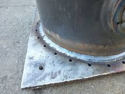 Spoina łącząca okrągły element z metalową płytą, widoczne otwory w płycie, szlifowane ślady po obróbce.