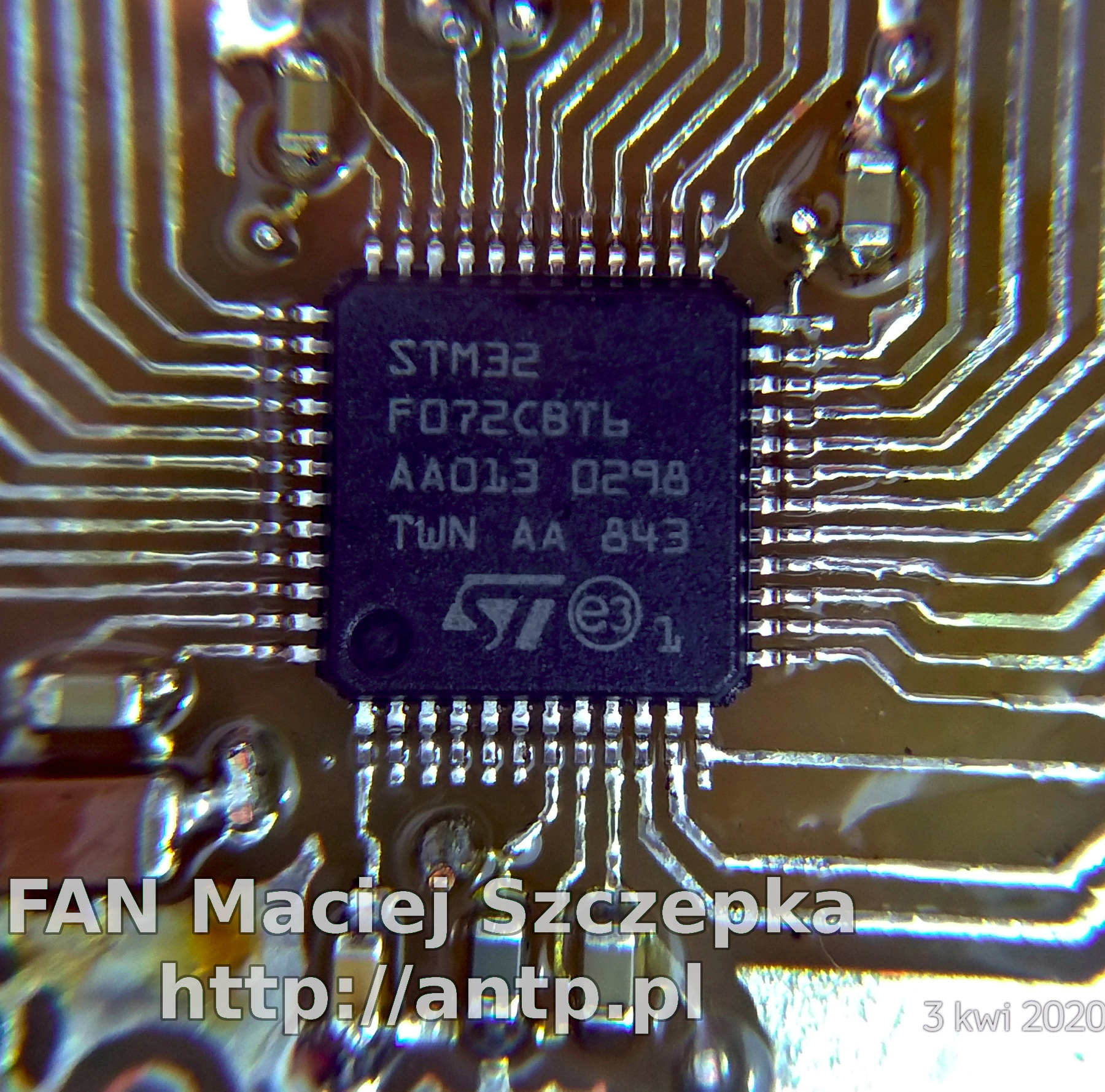 Zbliżenie na mikrokontroler STM32 F072CBT6 na płytce drukowanej z widocznymi ścieżkami i elementami SMD, sfotografowane z góry pod kątem.