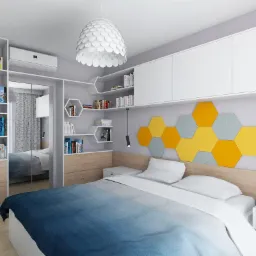 Nowoczesna sypialnia z łóżkiem z niebiesko-białą pościelą, zabudową meblową z szafą z lustrem, półkami w kształcie heksagonów i dekoracyjnymi panelami ściennymi w kolorach żółtym i szarym.