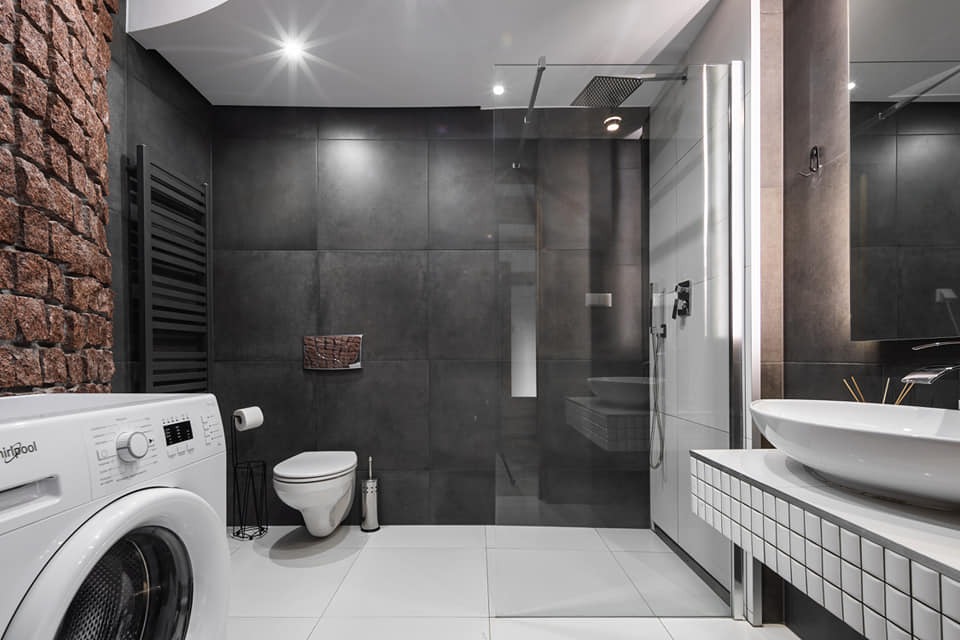 Nowoczesna łazienka z pralką, kabiną prysznicową typu walk-in, umywalką nablatową i ścianą z cegły rustykalnej.