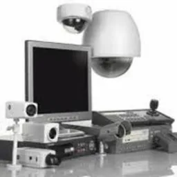 Zestaw urządzeń do monitoringu wizyjnego: kamery kopułkowe, kamery tubowe, rejestrator DVR, monitor LCD oraz kontroler z joystickiem, ułożone na białym tle.