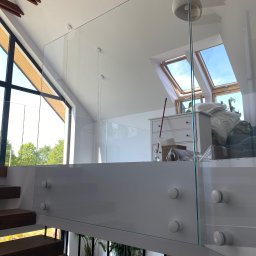 Nie Do Zbicia - Szklana balustrada z mocowaniami punktowymi w nowoczesnym domu z dużymi oknami i drewnianymi elementami. Widok z góry na schody i parter.