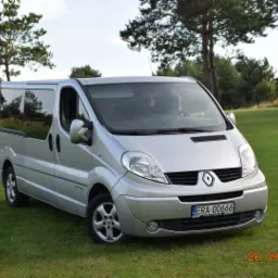 Srebrny Renault Trafic na trawiastym terenie z drzewami w tle, widoczne tablice rejestracyjne ERA 00666.