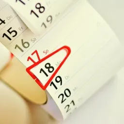 Kalendarz biurkowy z zaznaczoną datą 18-tego dnia miesiąca za pomocą czerwonego znacznika.