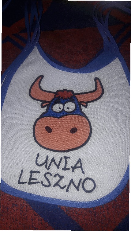 Dziecięcy śliniak z nadrukiem stylizowanego byka i napisem 'UNIA LESZNO' na szarym tle.