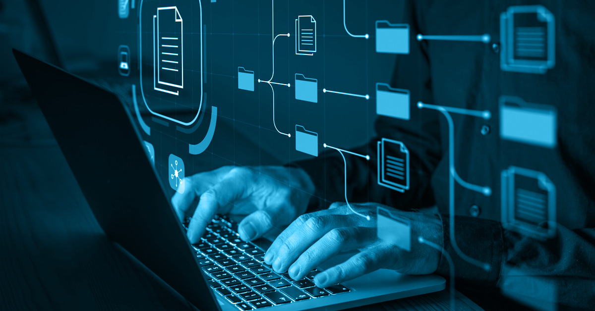 Dłonie programisty piszącego kod na laptopie z nałożonym schematem przepływu danych i ikonami folderów oraz plików w odcieniach niebieskiego.