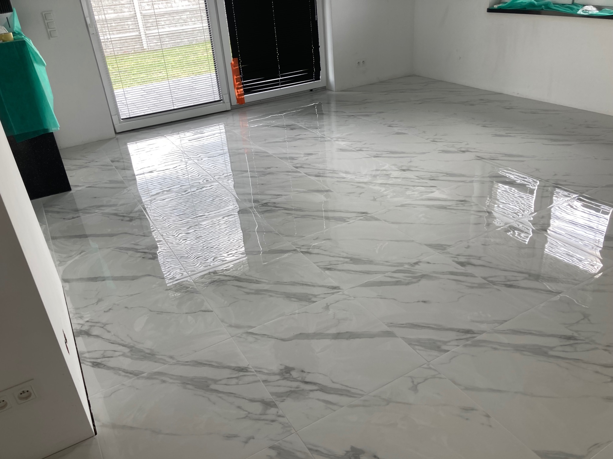 Błyszcząca, biała podłoga wyłożona płytkami imitującymi marmur, widok z perspektywy podłogi, z oknami w tle