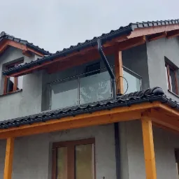 Nowoczesny dom w Sosnowcu z szarą elewacją i przeszklonym balkonem z metalową ramą.