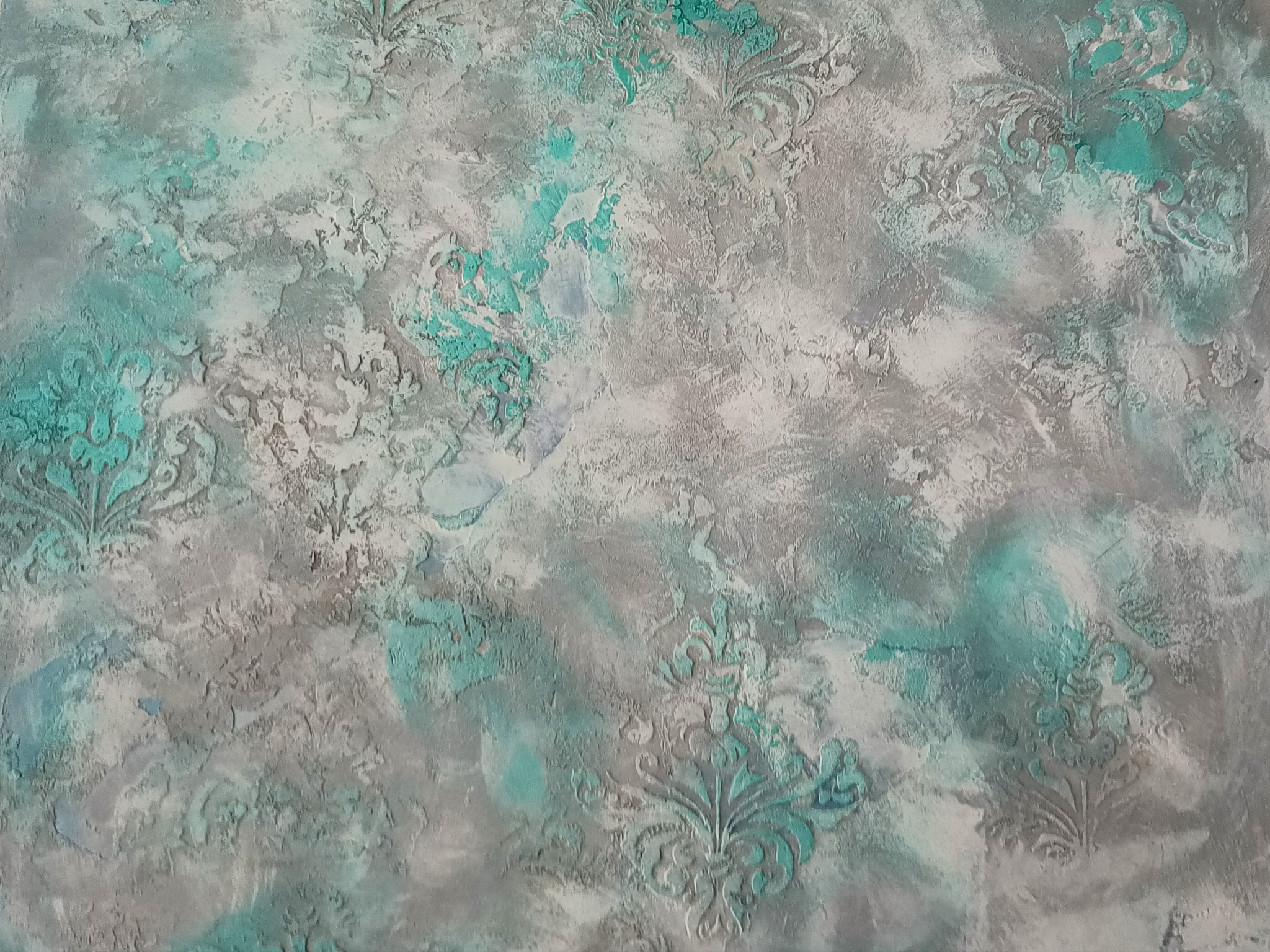 Dekoracyjna ściana z szaro-turkusową strukturą i motywem ornamentów roślinnych, wykonana techniką reliefową.