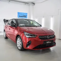 Czerwona Opel Corsa po detailingu w Jeleniej Górze, widoczny połysk lakieru i logo Car Shine Detailing na przednim zderzaku.
