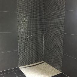 Czarna łazienka z kamieniami rzecznymi w strefie prysznicowej.