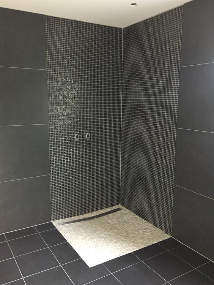 Czarna łazienka z kamieniami rzecznymi w strefie prysznicowej.