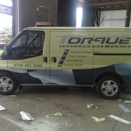 MPG Michał Pawelczyk - Określona okleina na samochodzie dostawczym Ford Transit z logo firmy Torque Performance Tuning oferującej diagnostykę pojazdów, chip tuning, remapowanie i hamownię, widoczne resztki folii i taśmy...