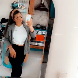 Osoba robiąca selfie w lustrze, w tle widoczna kuchnia z niebieskimi szafkami i srebrnym okapem.