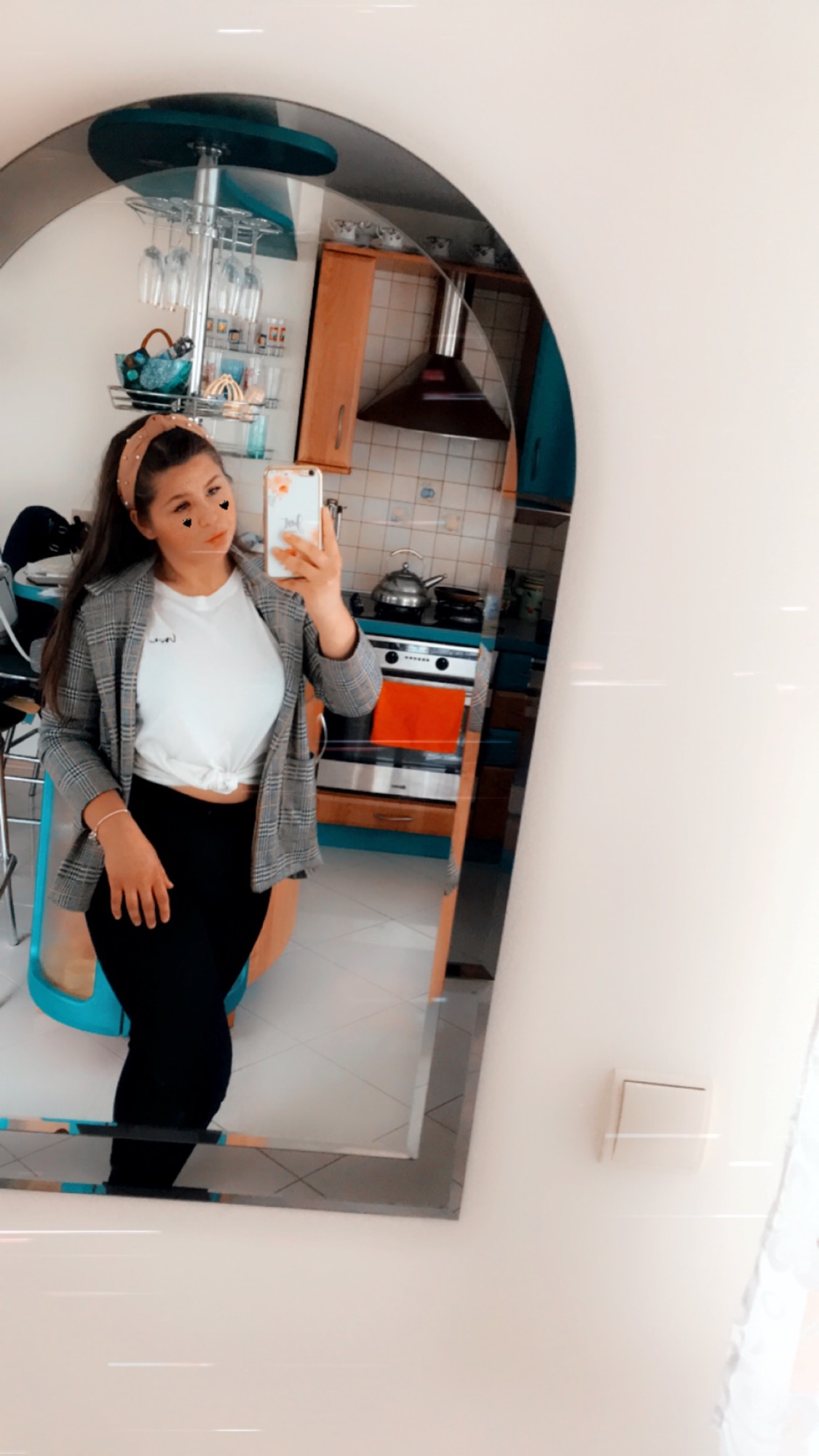 Osoba robiąca selfie w lustrze, w tle widoczna kuchnia z niebieskimi szafkami i srebrnym okapem.
