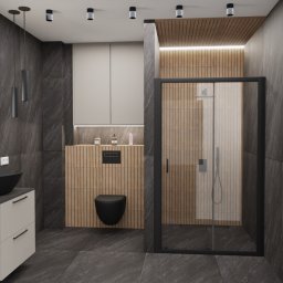 LA CASA STUDIO Iwona Wolska - Nowoczesna łazienka z czarną armaturą, okrągłym lustrem z podświetleniem LED i kabiną prysznicową. Ściany wykończone grafitową płytką imitującą kamień.