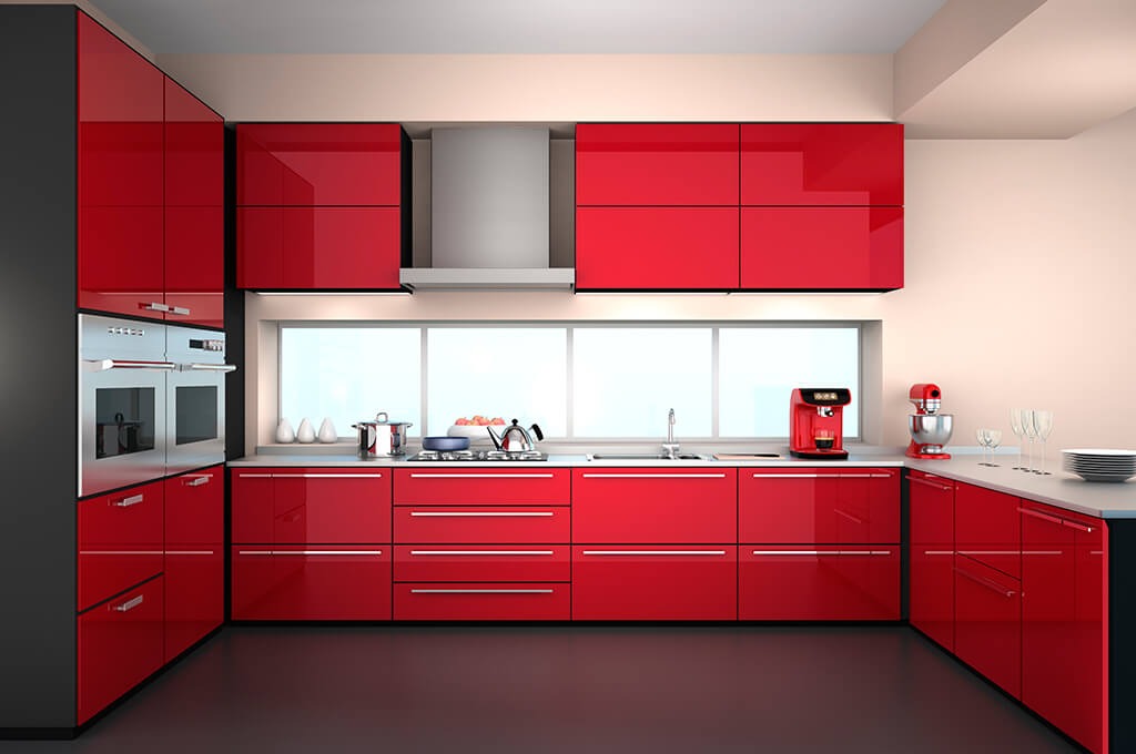 Nowoczesna kuchnia z czerwonymi, lakierowanymi frontami szafek, srebrnymi uchwytami, wbudowanymi piekarnikami i oknem z widokiem na zewnątrz.