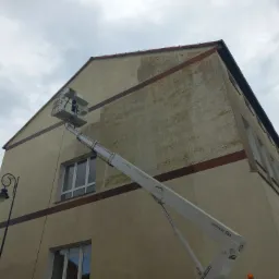 Prace przygotowawcze do malowania elewacji budynku w Szczecinie, widoczna podnośnik koszowy i fragment ściany z widocznym kontrastem pomiędzy czystą a zabrudzoną powierzchnią.