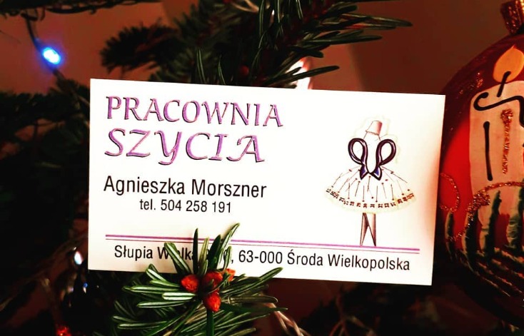 Wizytówka pracowni szycia Agnieszki Morszner z ilustracją sukienki wykonanej z nożyczek, umieszczona na tle choinki z ozdobami.