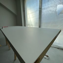 Rak-Fach Dawid Rak - Świeżo pomalowany sufit w pomieszczeniu z oknem zabezpieczonym folią malarską, widoczny fragment narzędzia malarskiego. Praca po malowaniu.