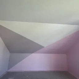 Pokój na poddaszu po malowaniu ścian w geometryczne wzory w odcieniach szarości, bieli i różu. Widoczne gniazdka elektryczne i surowa podłoga.