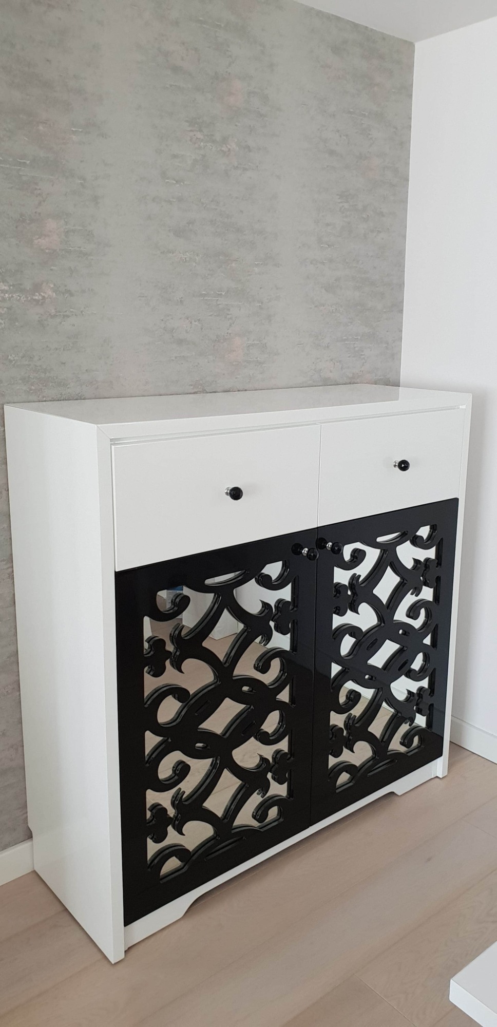 Szafka na wymiar. Lustro za czarnym elementem dekoracyjnym.