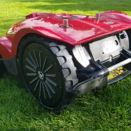 Czerwony autonomiczny robot koszący trawnik, model l250i, na tle soczystej zielonej trawy w słoneczny dzień.