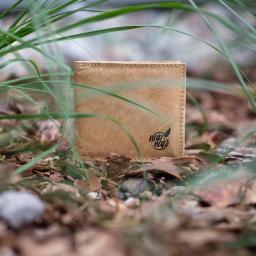 Napnap Justyna Napiórkowska - Portfel z ekologicznego materiału, z logo 'nap nap', umieszczony na ściółce leśnej, otoczony źdźbłami trawy.