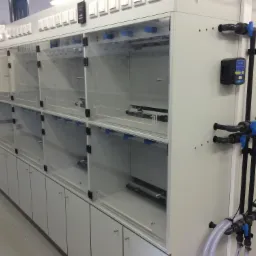 Rząd przezroczystych komór z instalacją wodną i zaworami, prawdopodobnie w laboratorium lub innym środowisku przemysłowym.