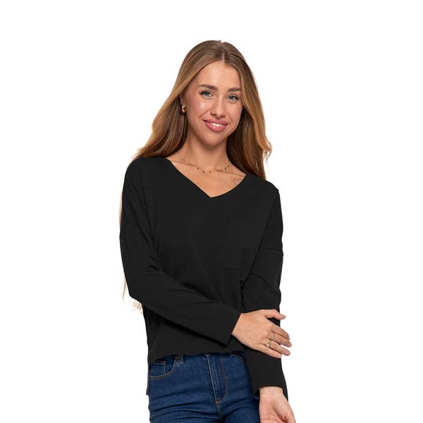 Uśmiechnięta blondynka w czarnej bluzce z długim rękawem i dżinsach, pozuje na białym tle. Widoczne złote kolczyki i delikatny naszyjnik.